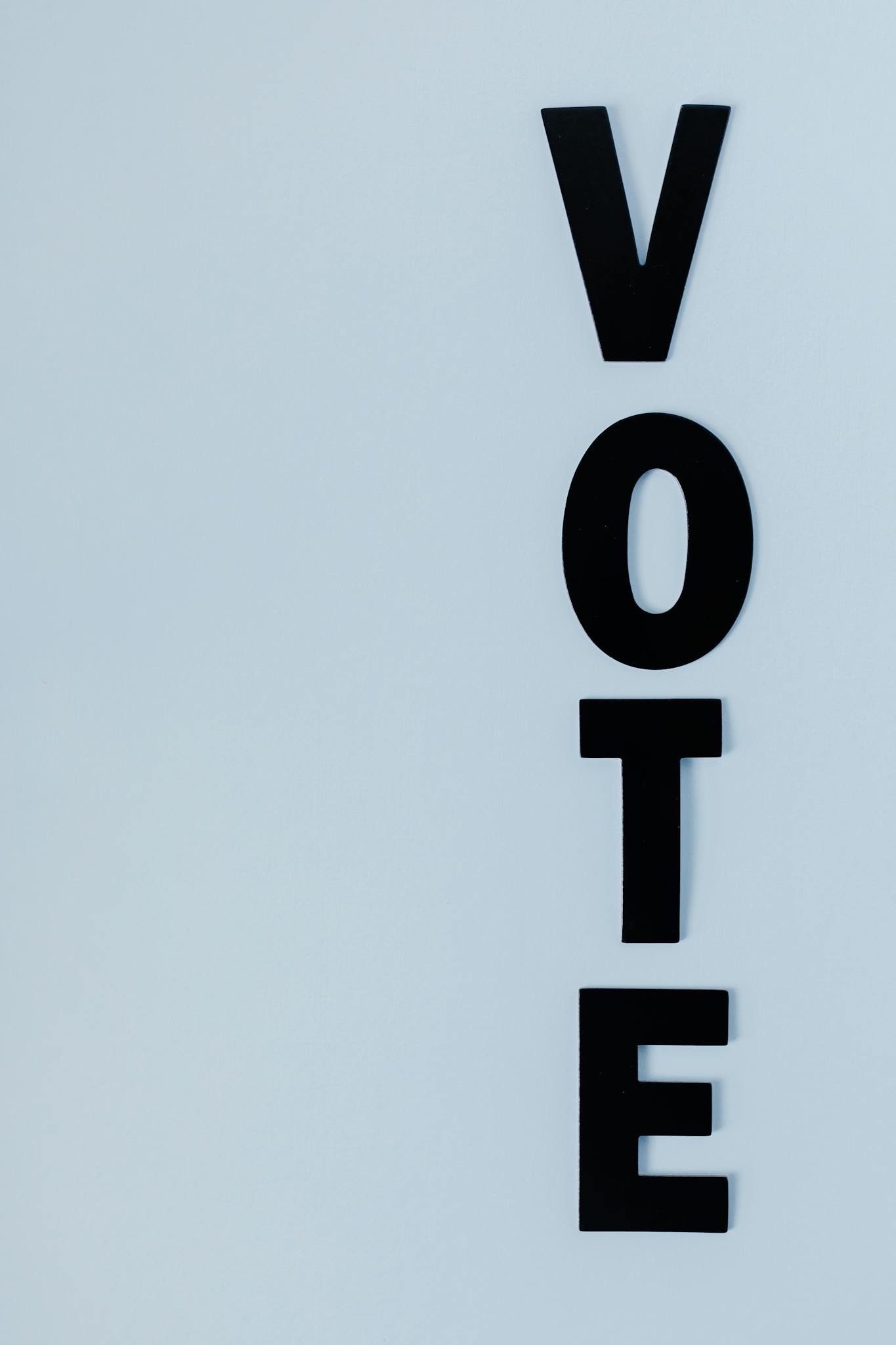Vertical arrangement of 'VOTE' letters on a light background for election themes.